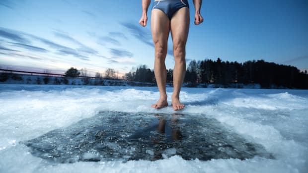 Cryotherapy for brown fat production. Man in bathing suit standing in front of whole in frozen lake,