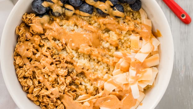 Vegan and gluten-free quinoa breakfast bowl with peanut butter, blueberries, and coconut flakes