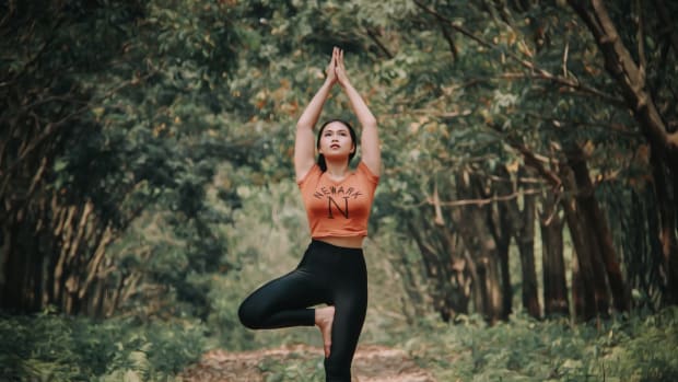 woman doing yoga in the forest to activate autophagy