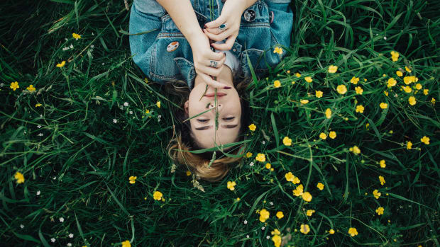 woman lying in green meadow surrounded by yellow flowers