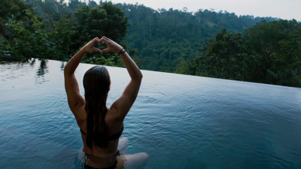 Kirtan quiets the mind and opens the heart. Woman sitting in infinity pool looking over Ubud.