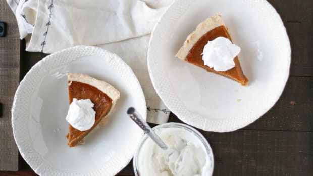 paleo pumpkin pie slices with whip cream on two white plates.