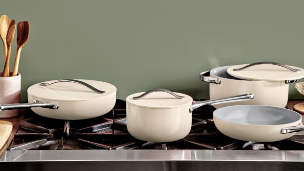 A set of white Caraway cookware on a stovetop.