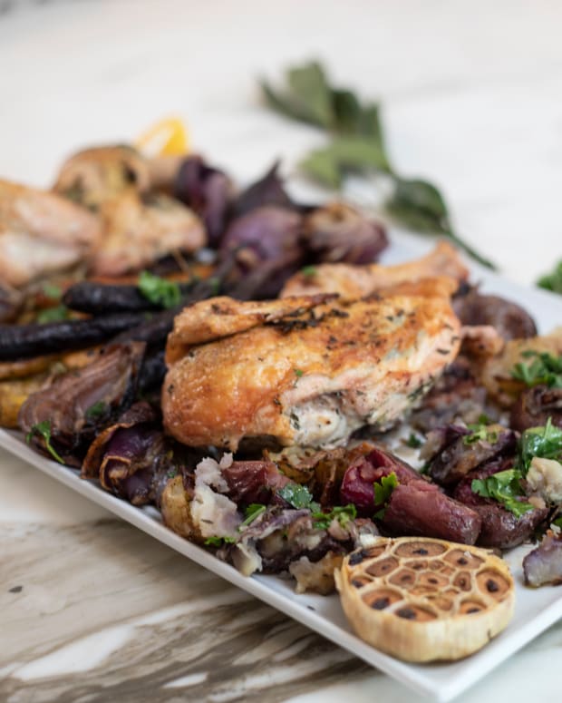 roasted sheet pan chicken with rainbow carrots and potatoes on a platter.