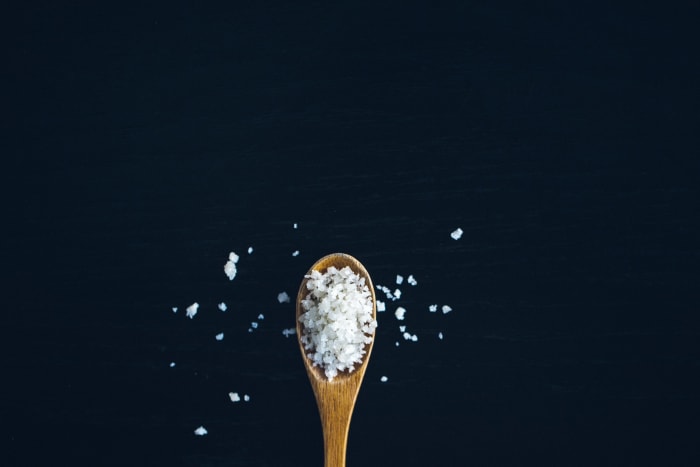 Una cucharadita de madera llena de sal marina en escamas que agregará sabor a cualquier comida.