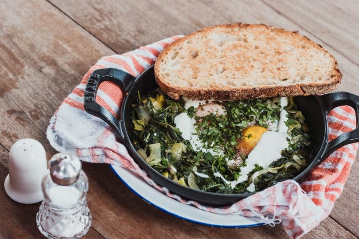 cast iron dish with egg and greens and toast