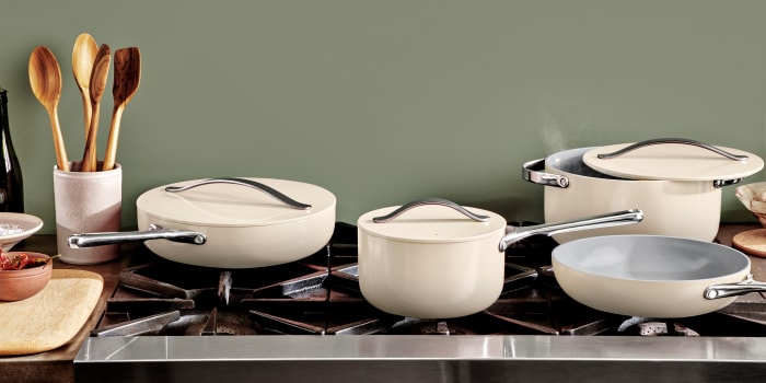 A set of white Caraway cookware on a stovetop.