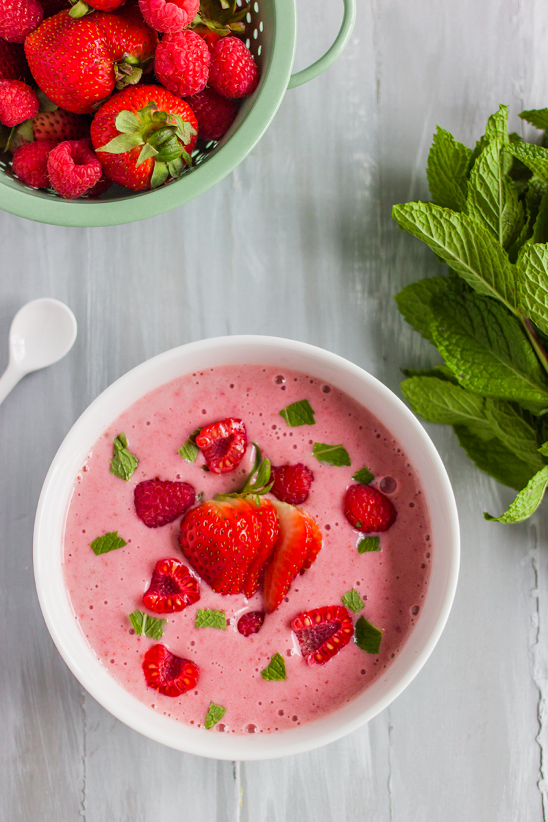 Plant based smoothie bowl garnished with fresh mint, strawberries, and raspberries
