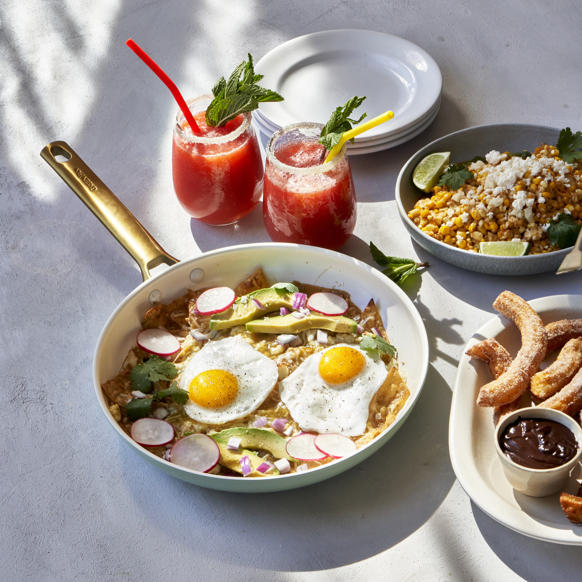 A brunch spread in the sunshine, with watermelon mint drinks, churros, and chilaquiles.