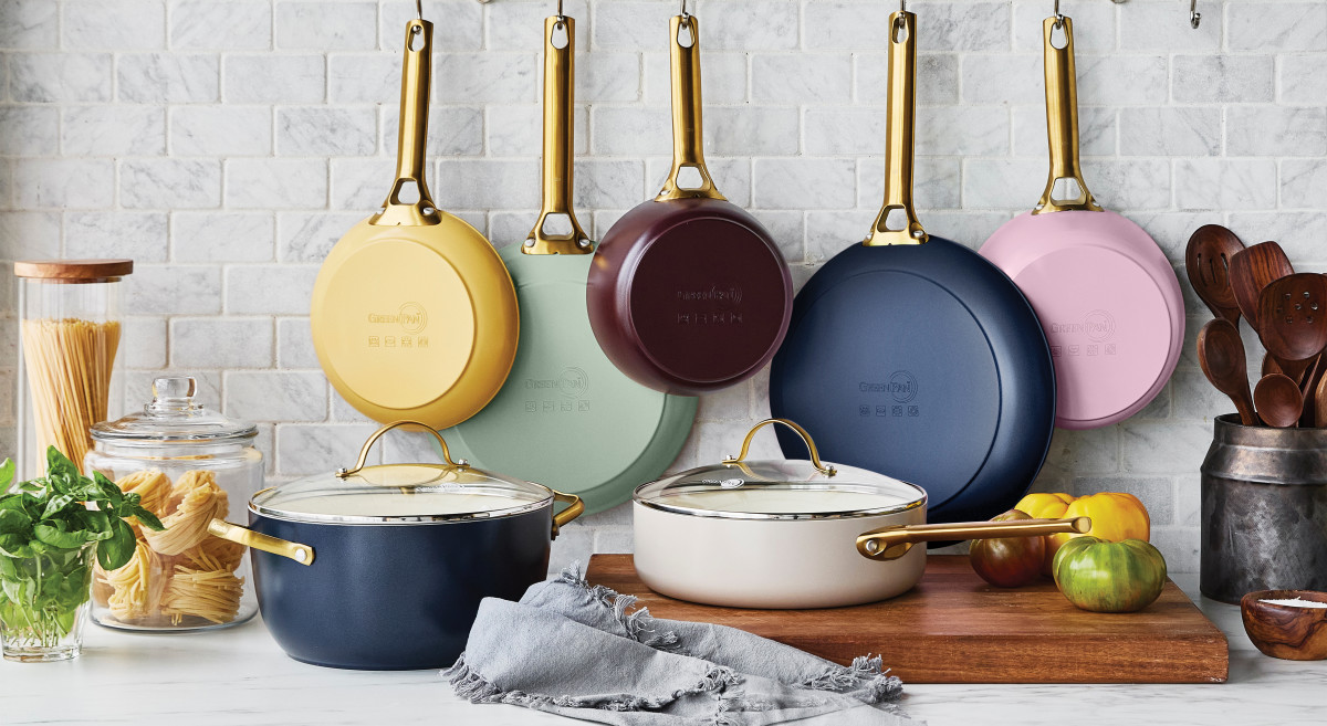 Colorful set of GreenPan nonstick non-toxic ceramic pans hanging on the wall in a kitchen.
