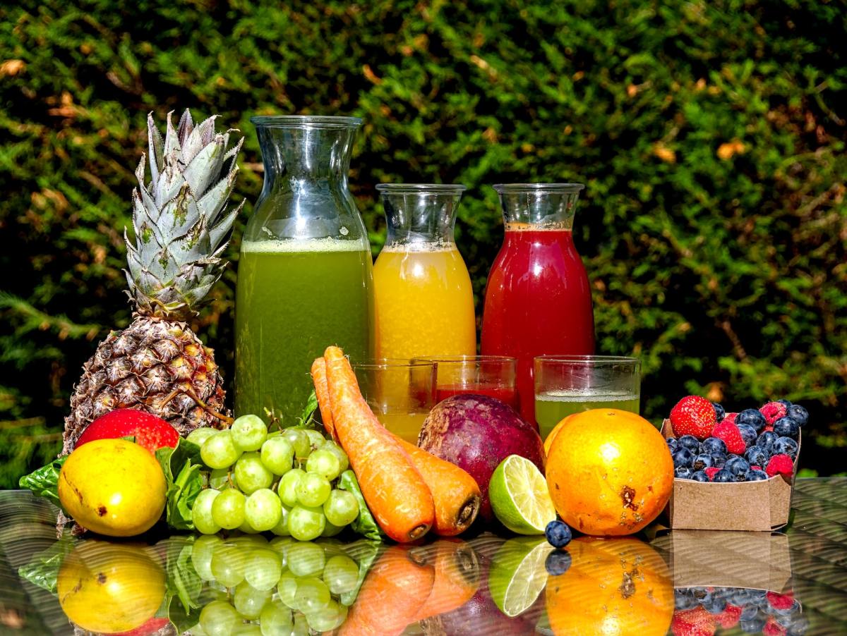 juices and fruits and vegetables on a table outside