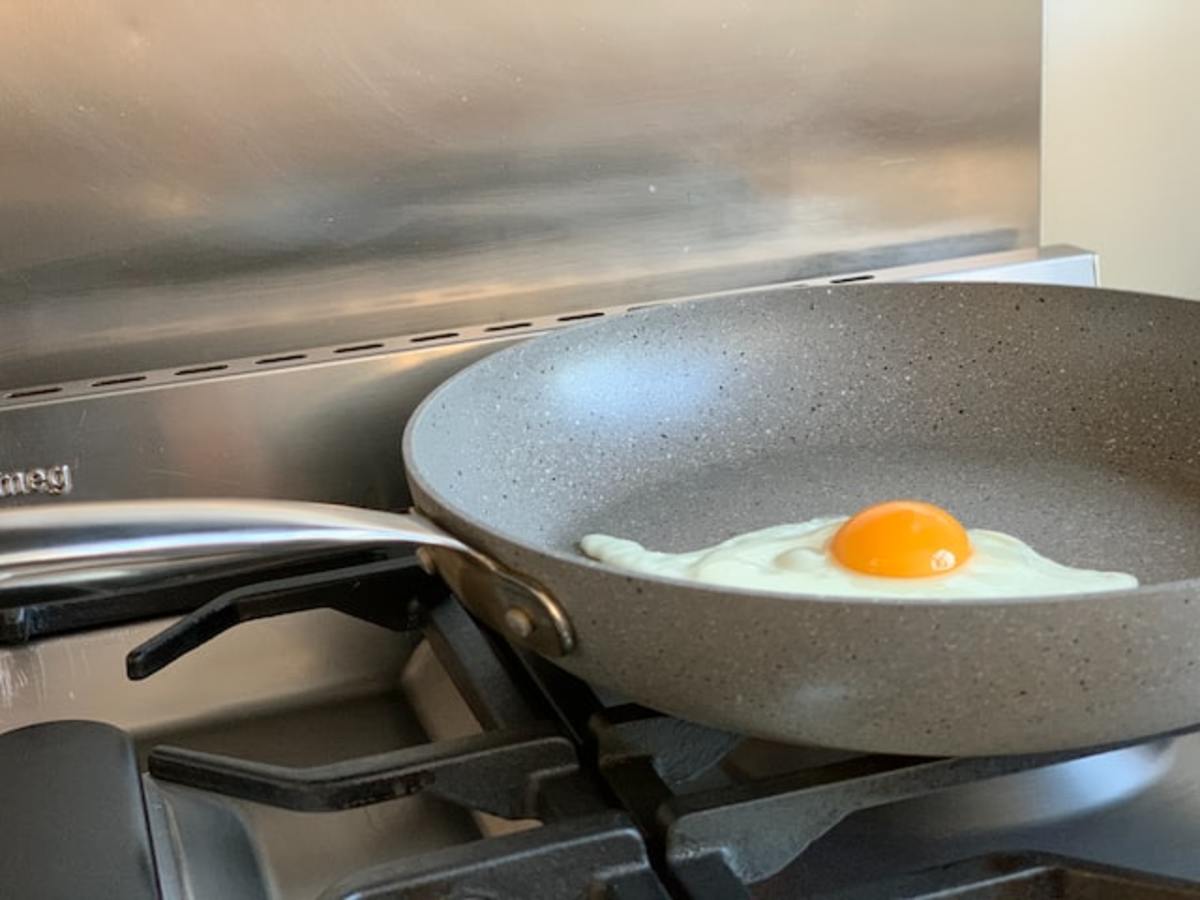 Nonstick pan on the stove with an egg in it.
