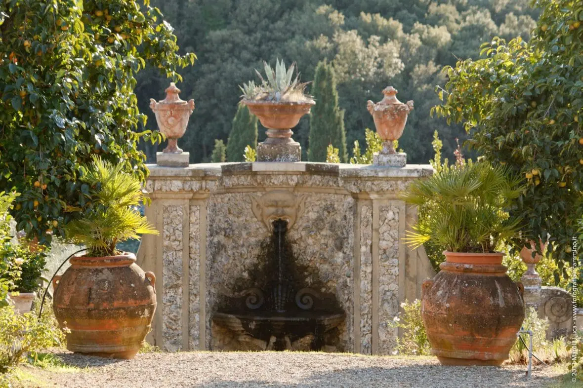 Historic stone fountain and urns in an Italian villa garden with cypress trees