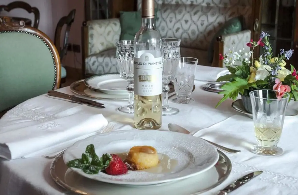 Elegant dining table set with white wine, fresh dessert, and floral centerpiece at an Italian