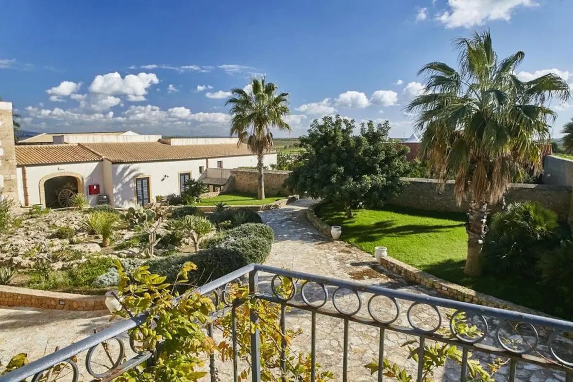 Mediterranean villa courtyard with palm trees and manicured gardens under blue sky