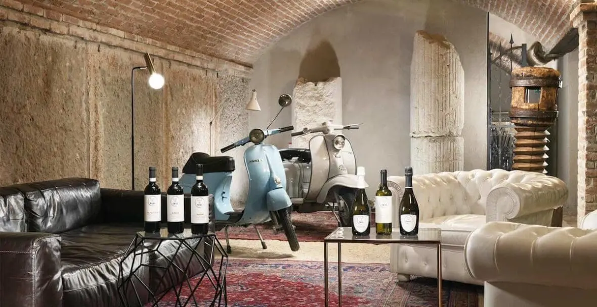 Luxury wine hotel lounge with Vespa scooters, vintage wine bottles, and leather seating