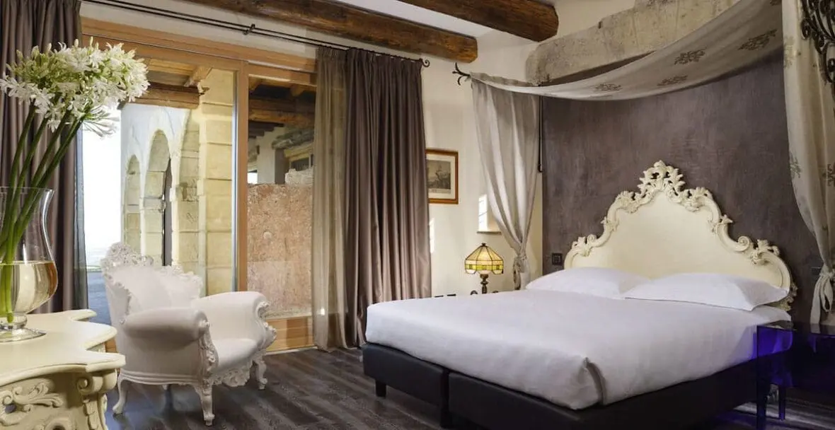 Luxurious hotel bedroom with ornate cream headboard, white bedding, and elegant furnishings