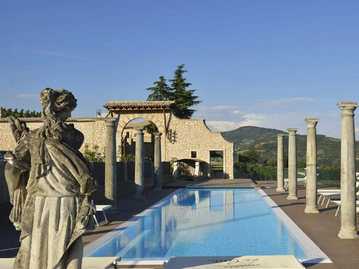 Luxurious poolside terrace at an Italian wine estate hotel with classical columns and countryside