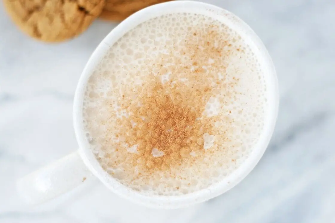 A white mug of gingerbread latte on a white marble countertop.