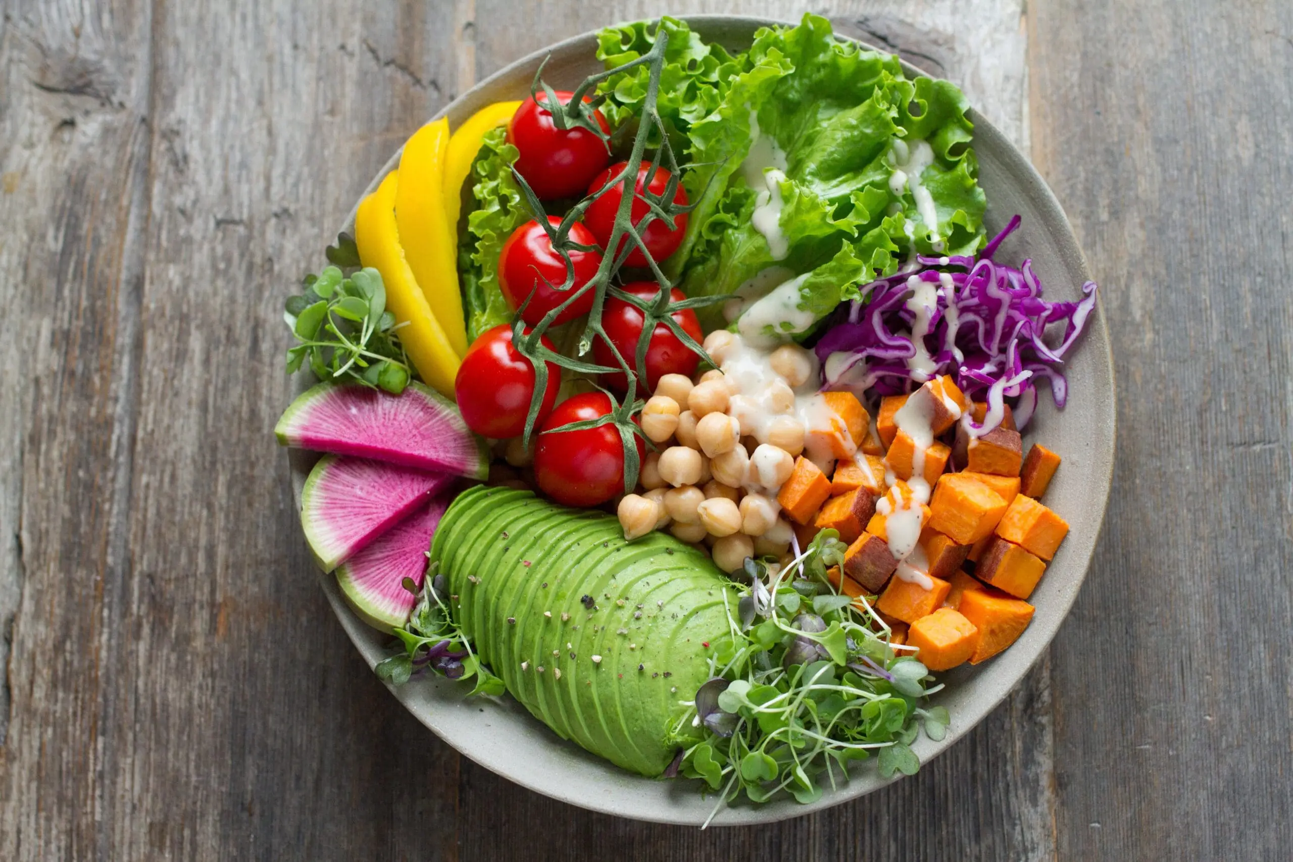 Colorful Buddha bowl with leafy greens, tomatoes, avocado, chickpeas, and roasted vegetables
