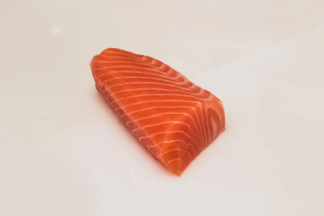 Image of raw filet of salmon on plain white background for use in a healthy salmon burger recipe