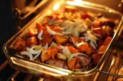 Roasted sweet potatoes and onions in a baking dish in the oven