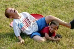 Two young children playing together on grass outdoors