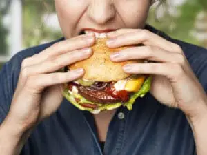 Person eating a plant-based burger with lettuce and tomato