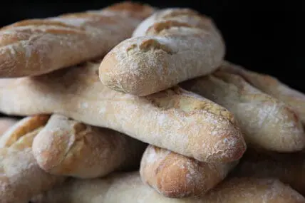 Crusty French baguettes stacked on a dark surface
