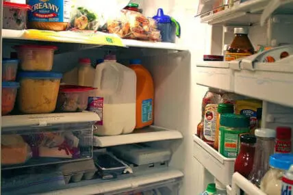 Disorganized refrigerator interior with various food items and containers scattered across shelves