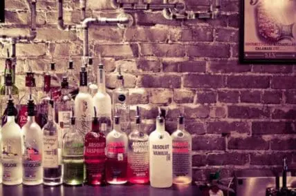 Assorted vodka bottles displayed on a shelf against a brick wall