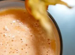 A smoothie with foam texture topped with a sliced banana