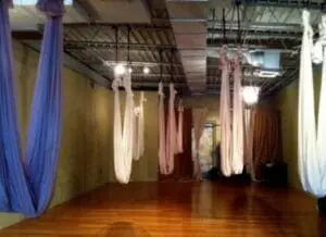 Aerial yoga studio with suspended fabric hammocks and wooden floor