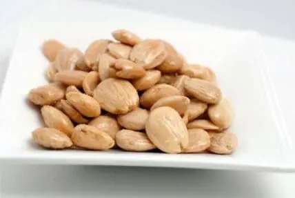 A pile of roasted cashews on a white square plate
