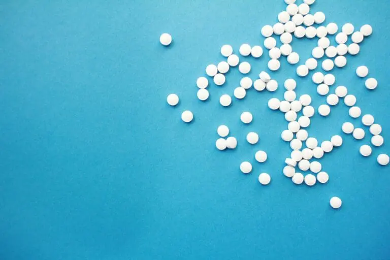 Image of a spilled white pills on a bright blue background showing that how to prevent Alzheimer's may be managing mental health disorders.