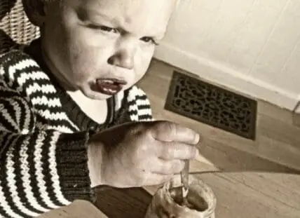 Toddler in striped sweater eating from a bowl with a spoon
