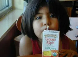 Child drinking organic apple juice from a carton with straw