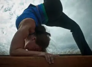 Person practicing a forward bend yoga pose outdoors in winter conditions