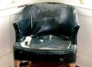 Worn black leather armchair with torn upholstery and visible damage
