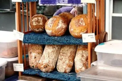 Artisan organic breads displayed on wooden shelving at a bakery counter