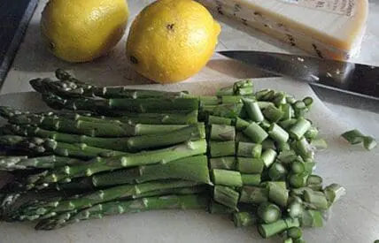 Fresh asparagus and peas with lemons and butter on a cutting board