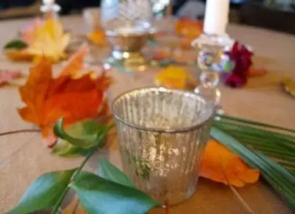 Autumn table setting with fall leaves, candles, and textured glassware