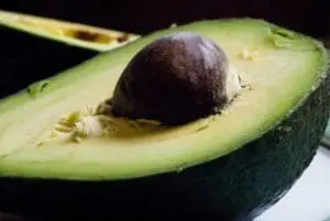 Halved avocado with pit exposed on black background