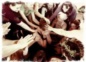 Group of people placing hands together in a circle during a baby blessing ceremony