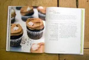 Open cookbook page showing chocolate cupcakes with frosting in black liners