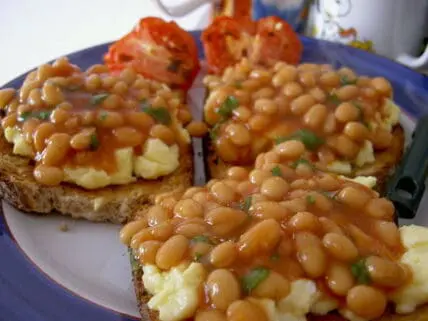 Baked beans and scrambled eggs on whole grain toast with green garnish