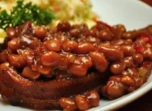 Baked beans served on toast with coleslaw and potato salad on a white plate