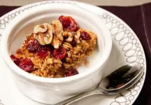 Bowl of granola with dried cranberries and walnuts on a decorative white plate