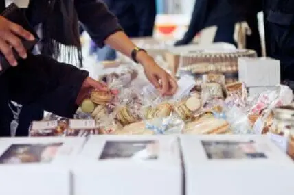 Person selecting homemade baked goods and packaged foods from a table display