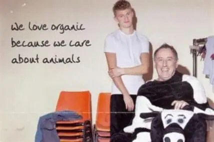 Two people posing with cow plush toys next to text about loving organic food for animal welfare